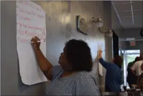  ?? BRIANA CONTRERAS — THE MORNING JOURNAL ?? Christa Battle of Elyria writes down ideas brainstorm­ed by her group during a Reimagine Downtown meeting June 12 at Oven 51 Pizza Bistro & Gamery.