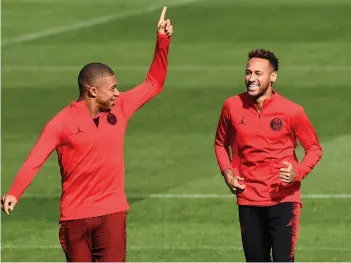  ?? AFP ?? Paris Saint- Germain player Neymar ( right) jokes with team mate Kylian Mbappe during their training session at the Camp des Loges camp in Saint- Germain- en- Laye, near Paris, on Monday, eve of their UEFA Champions League match against Liverpool. —