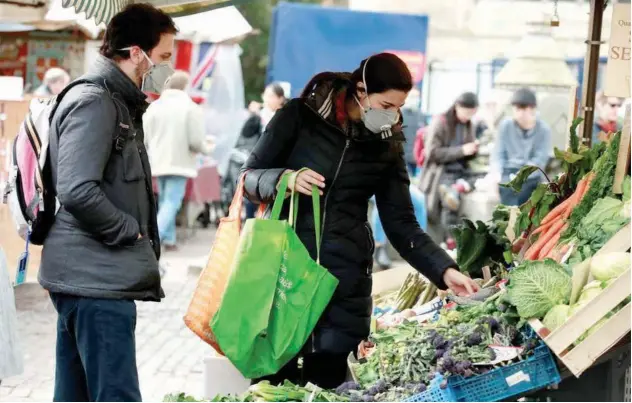  ?? File/reuters ?? ↑
Residents, wearing face masks, shop at a market in Cambridge, Britain.