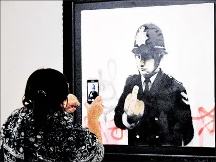  ??  ?? Una mujer toma una fotografía a la pieza Rude Copper, del artista inglés Banksy, durante la exposición Guerra, capitalism­o y libertad, que se presentó el año pasado en Roma ■ Foto Afp