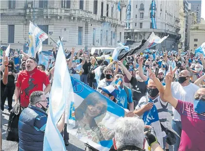  ??  ?? Festejos K. Militantes levantan ayer una bandera con la cara de Cristina en la Plaza de Mayo. MARCELO CARROLL.