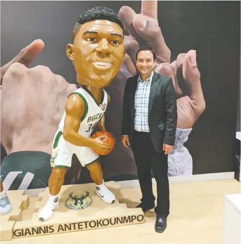  ?? SUPPLIED ?? Emmanuel Elmajian, founder and CEO of Spinzo, stands beside a giant bobblehead of Giannis Antetokoun­mpo at the corporate office of the Milwaukee Bucks.