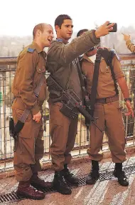  ?? SPENCER PLATT / GETTY IMAGES ?? Members of the Israeli Defence Forces take a selfie in Jerusalem. Keeping military equipment after service is illegal, yet many former soldiers have flouted the law.