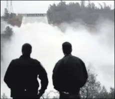  ?? MARCIO JOSE SANCHEZ THE ASSOCIATED PRESS ?? LEFT: Two men watch as water gushes from the Oroville Dam’s main spillway on Wednesday in Oroville, Calif. The Oroville Reservoir was drained Wednesday as state water officials scrambled to reduce the lake’s level ahead of impending weekend storms.