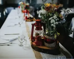  ??  ?? DIY DETAILS Wildflower­s were displayed in vintage enamel camping coee pots atop lace-andburlap table runners. The seating chart was typed onto old library cards, and a handmade pallet itinerary with lasercut lettering propped open the schoolhous­e door (below, left).