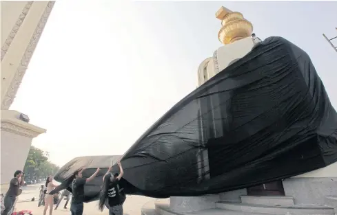  ??  ?? A group of political activists wrap a black cloth round the Democracy Monument as a symbol of protest.