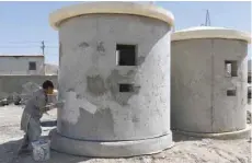  ?? — AFP ?? An Afghan worker paints a concrete security booth in Kabul.