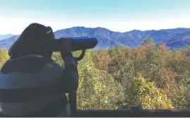  ?? THE ASSOCIATED PRESS ?? Amber McCarter, a 22-year-old woman from Tennessee who is colorblind, looks out from Mt. Harrison at the Ober Gatlinburg resort through a viewfinder designed to help her see more colors.