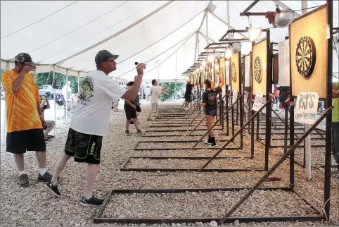  ?? PHOTOS BY MEGAN DAVIS/MCDONALD COUNTY PRESS ?? Throughout the weekend, darters gather under the white-top tent to practice their shots in hopes of ultimately winning the cash grand prize. The event is open to the public and locals are encouraged to stop by Wayside Campground and take part.