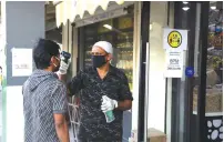  ?? ( Christophe­r Pike/ Reuters) ?? A MAN has his temperatur­e taken outside a store in Dubai in April.