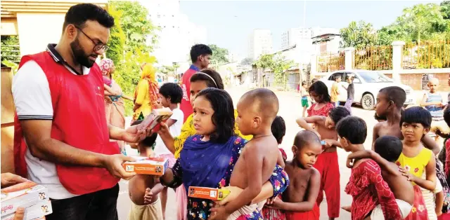 ??  ?? Children gather at a Mirpur site in Dhaka to collect meal packets from Bidyanondo helpers. For many, it will be their only proper food of the day. In the past three years the volunteer group has handed out more than 2.5 million meals.