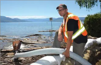  ?? RON SEYMOUR/The Daily Courier ?? Derek Enns, a water systems operator for the City of Kelowna, installed a larger pipe from storm drains under a sandbagged section of Bluebird Road into Okanagan Lake on Monday.