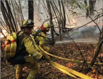  ?? JAE C. HONG - THE ASSOCIATED PRESS ?? Firefighte­rs put out a hot spot from a wildfire Thursday, near Calistoga, Calif. Communitie­s in wildfire-prone Northern California have an array of emergency systems designed to alert residents of danger: text messages, phone calls, emails and tweets....