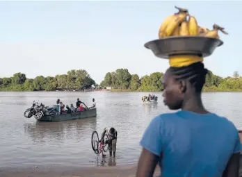  ?? AP LEO CORREA/ ?? A woman waits for a boat so she may cross the Gambia River on Sept. 28 in Bansang, Gambia.