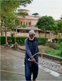  ?? Thomson Reuters Foundation ?? A gardener washes a walkway in front of a house in lahore’s Johar Town neighbourh­ood. —