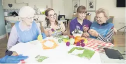  ??  ?? ● Bryn Seiont Newydd residents enjoy an art project run by Age Cymru. Above: Pendine’s Nia Lloyd and Kelly Barr (Cartrefi Project Co-ordinator) admire fruit made from recycled paper cups with Daphne Eagan and Owenna Jones; right, carer Angela Williams and Kelly Barr work with Annie Peers. Pictures: JANE WIDDOWSON