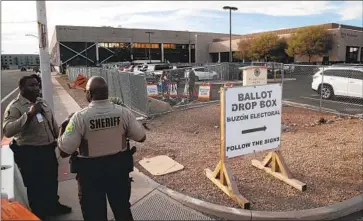  ?? Gina Ferazzi Los Angeles Times ?? SECURITY GUARDS watch over a ballot drop-off site Monday in Phoenix. Election officials have received threats, and a federal judge has barred a right-wing group from sending armed people to monitor drop boxes.