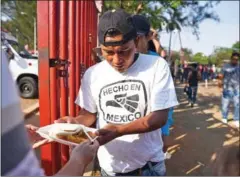  ?? RAZO/AFP VICTORIA ?? Central American migrants taking part in the ‘Migrant Via Crucis’ caravan towards the United States receive breakfast as they camp at a sport complex in Matias Romero, Oaxaca State, Mexico, on Wednesday.