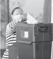  ?? RICARDO RAMIREZ BUXEDA/ORLANDO SENTINEL ?? Vote by mail attendant Alicia Pagan uses tongs to deposit ballots at the Orange County Supervisor of Elections on Aug. 18.