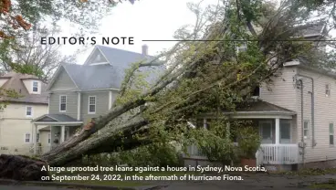  ?? ?? A large uprooted tree leans against a house in Sydney, Nova Scotia, on September 24, 2022, in the aftermath of Hurricane Fiona.