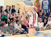  ?? [PAUL HELLSTERN, THE OKLAHOMAN] ?? The University of Oklahoma’s athletics mascot trades high-fives Friday with Bodine elementary school students, as the children cheered an Oklahoma City Community Foundation donation to acquire playground equipment for their southeast-side school.