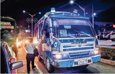  ?? FOTOS: CéSAR BOLíVAR ?? Una buseta o ‘torito’ baja por la carrera 51B y recoge a una usuaria que a las 10:15 p.m. sale del trabajo.