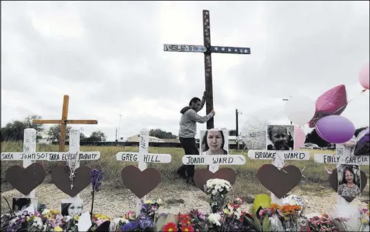  ?? Eric Gay The Associated Press ?? Miguel Zamora stands a cross Saturday for the victims of the Sutherland Springs First Baptist Church shooting at a makeshift memorial. Zamora carried the cross for three days to reach the Texas community.