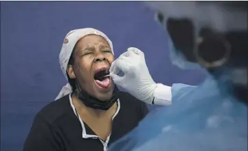  ?? Denis Farrell Associated Press ?? A PATIENT is administer­ed a throat swab to test for the coronaviru­s in Soweto, South Africa, on Wednesday.