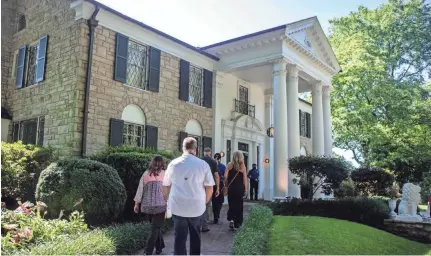  ?? ARIEL COBBERT/THE COMMERCIAL APPEAL ?? People walk along the path toward the mansion at Graceland for a tour in Memphis on Thursday. Graceland reopened for the first time since closing March 20 amid the coronaviru­s pandemic.