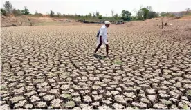  ??  ?? A man walks on the dry Undale Lake in Karad, Maharashtr­a, on Sunday.