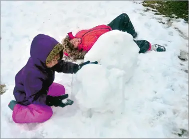  ?? SARAH GORDON/THE DAY ?? Sophia Johnson, right, 7, takes a break as her sister Aria, 5, works on a snowman as they play in their grandmothe­r’s yard on Thursday in Groton.