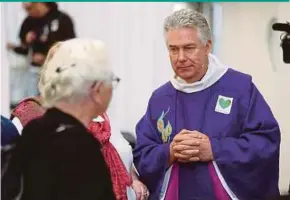  ?? AFP PIC ?? Dean Lawrence Kimberley speaking with a member of his congregati­on after a service at the ‘Cardboard Cathedral’ in Christchur­ch yesterday.