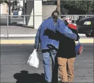  ?? PHOTO TOM BODUS ?? Richard and Rhonda Sewell cross State Street Thursday in El Centro after receiving their free Thanksgivi­ng dinners at the Elks Lodge parking lot.