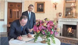  ?? FILE/PETE SOUZA/THE WHITE HOUSE/STICHTING KUNSTBOEK VIA AP ?? French President François Hollande signs the guest book in 2014 as then President Barack Obama looks on at the White House. For the state visit, a centerpiec­e bouquet of early spring flowers in the French style was presented in a gilded pedestal...