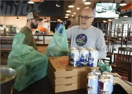  ?? LAUREN A. LITTLE – MEDIANEWS GROUP ?? Chef Billy Yoder, left, and general manager Randy McKinley package takeout at the Sly Fox Taphouse at the Knitting Mills in Wyomissing on Wednesday. They have a table set up right inside the door and will run orders out to your car.