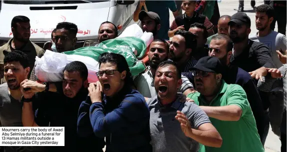  ??  ?? Mourners carry the body of Awad Abu Selmiya during a funeral for 13 Hamas militants outside a mosque in Gaza City yesterday