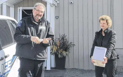  ?? LYNN CURWIN/TRURO NEWS ?? Truro Police Constable Peter Cullip tries some of the Raging Crow hand sanitizer as Jill Lindquist, president of the distillery, brings over a case of the product. Raging Crow donated several bottles of sanitizer to the police service this week.
