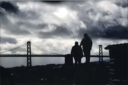  ?? KARL MONDON — STAFF PHOTOGRAPH­ER ?? With storm clouds blowing through on Friday, Diego Martinez, right, fishes with his friend Cristian Garduno in San Francisco.