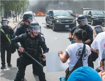  ?? PHOTO AFP ?? Les affronteme­nts entre manifestan­ts et forces de l’ordre ont repris de plus belle, hier, en début de soirée, à Minneapoli­s. Des policiers tentent de repousser la foule alors qu’un véhicule de patrouille est la proie des flammes derrière eux.