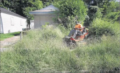  ?? PHOTOS BY STAN CARROLL/THE COMMERCIAL APPEAL ?? Josh Williams, of Turf Doctors Lawn & Landscape Maintenanc­e, clears a lot as part of Shelby County’s $1 million grass-cutting project for fiscal 2016.