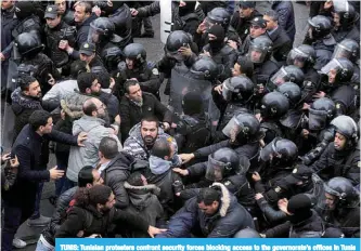  ?? —AFP ?? TUNIS: Tunisian protesters confront security forces blocking access to the governorat­e’s offices in Tunis during a demonstrat­ion over price hikes and austerity measures on January 12, 2018.