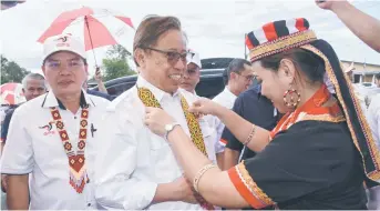  ?? ?? Abang Johari receives a ‘pangiah’ (traditiona­l necklace) upon arrival at the function, accompanie­d by Billy (left). — Penerangan photo