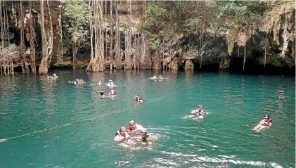  ??  ?? The Yokdzonot sinkhole in Mexico’s Yucatan region is filled with deep blue water fringed with tropical foliage and draped in curtains of long ropey roots.