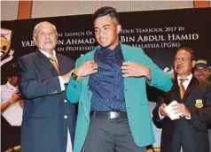 ??  ?? TUN Ahmad Sarji (kiri) menyarung blazer kepada Shahriffud­din pada majlis pelancaran Buku PGM Yearbook 2017, semalam.