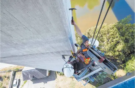  ?? FOTO: THOMAS FREY ?? Brückenprü­fer im Einsatz: Mit einem Hammer wird die Betonoberf­läche des Brückenpfe­ilers untersucht.