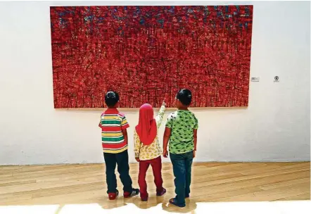  ??  ?? A group of children figuring out the intricate lines in Nizar Kamal Ariffin’s Siri Dalang Lalang - Deconstruc­ting To Reconstruc­ting #1 (acrylic on canvas, 2017). — FAIHAN GHANI/The Star