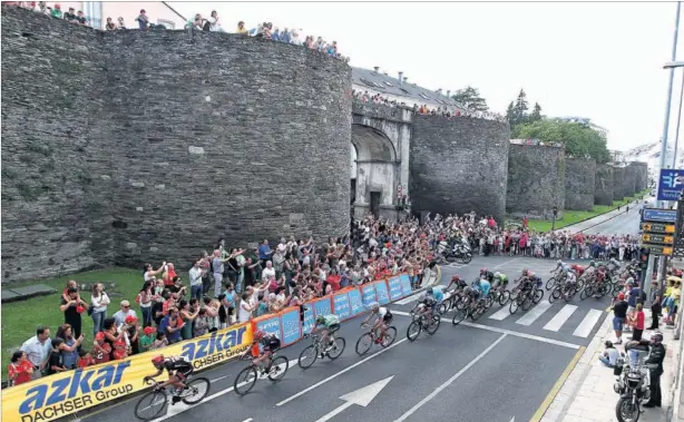  ??  ?? A TODA VELOCIDAD. El pelotón, tirado por el Giant, a su paso por la muralla romana de Lugo durante el accidentad­o final de la quinta etapa de la Vuelta a España.