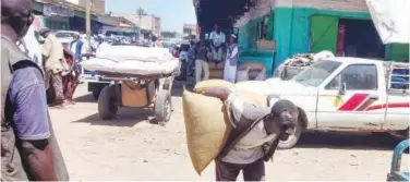  ?? Agence France-presse ?? ↑
A worker carries grain sacs at a market in Sudan’s eastern state of Gedaref on Thursday.