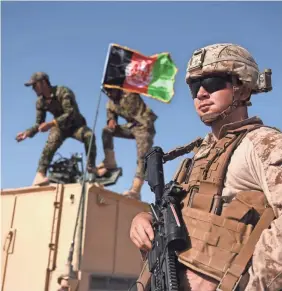  ?? WAKIL KOHSAR/AFP VIA GETTY IMAGES ?? A U.S. Marine looks on as Afghan National Army soldiers raise the Afghan National flag on an vehicle during a training exercise in Helmand province. U.S. forces have started pulling out of Afghanista­n.