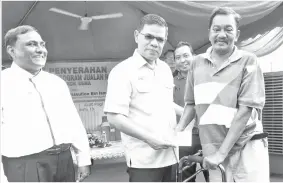  ??  ?? SAIFUDDIN menyampaik­an bantuan zakat kepada Zulkefeli Ismail (kanan) pada majlis penyerahan Zakat SSM sempena Program Jualan Rakyat Parlimen Pokok Sena di padang Awam KEDA, pada Ahad. -Gambar Bernama